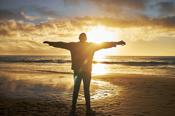 Worship, sunrise and silhouette of man at the beach standing with arms raised. Faith, religious and...