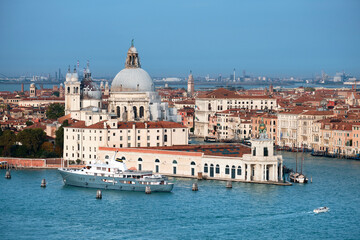 Fototapeta na wymiar Aerial view of Punta Dogana with Santa Maria della Salute. Bird view of blue water of Venetian lagoon and Grand Canal. Bright day with blue sky and sea.