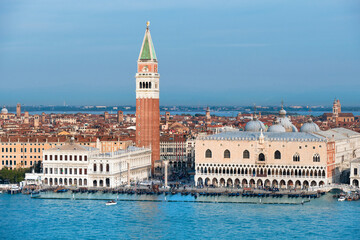 Aerial view of Doge's Palace or Palazzo Ducale and Campanile di San Marco, St. Mark's Campanile or bell tower and water of Venetian lagoon with gondolas. Bright day with blue sky and sea.