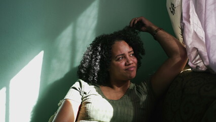 Relaxed young woman sitting on couch in contemplation. An African young woman relaxing at home