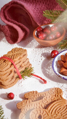 Obraz na płótnie Canvas Speculoos or Spekulatius, Christmas biscuits, with cranberry berries, almonds on a table with kitchen towel, fir twigs. Traditional German sweets, cookies for Christmas or Advent, wintertime snacks.
