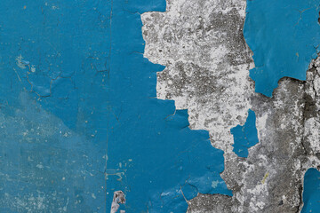 Blue peeling paint on the wall. Old concrete wall with cracked flaking paint. Weathered rough painted surface with patterns of cracks and peeling. High resolution texture for background and design.