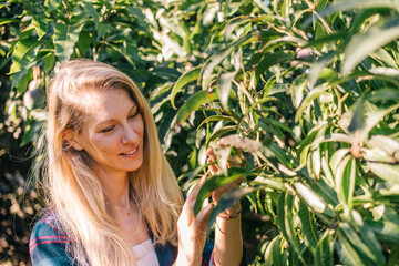 Beautiful and young caucasian woman taking care of the plants in a garden