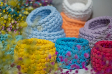 Obraz na płótnie Canvas close-up of a beautiful colorful crochet baskets on colorful flower background. Handicraft advertising. a nice hobby in the winter evenings. Sustainable, organic lifestyle advertising. 