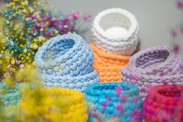 close-up of a beautiful colorful crochet baskets on colorful flower background. Handicraft advertising.  a nice hobby in the winter evenings. Sustainable, organic lifestyle advertising. 