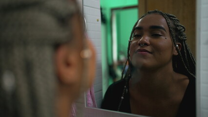 One hopeful black latina girl looking at herself in mirror smiling with HOPE