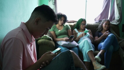 Group of hispanic people sitting on couch looking at smartphone device. People hanging out staring...