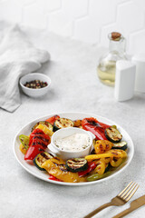 Grilled vegetable, bell sweet pepper and zucchini with sauce on a white plate and grey background. Healthy vegan food.