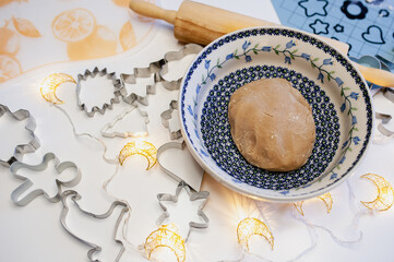 Dough in a bowl for gingerbread for christmas, molds in the form of animals, rolling pin, bokeh