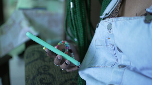 A Black Hispanic Girl Looking At Smartphone Device. A Young Latina Woman Scrolling Through Social Media