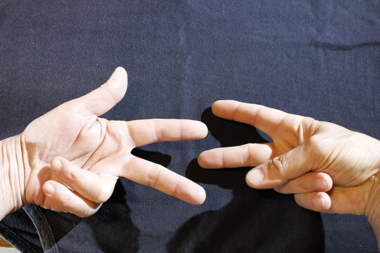 Posici&oacute;n de las manos de un hombre con los dedos extendidos haciendo el gesto de un juego de falanges, forma un original dise&ntilde;o con fondo negro