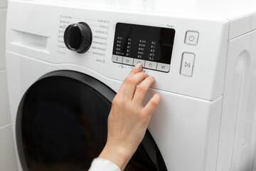 Close-up of a hand selecting a program with a finger while pressing on a washing machine