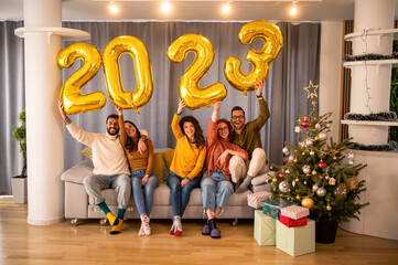 Group of young beautiful people in casual clothing carrying gold colored numbers and smiling