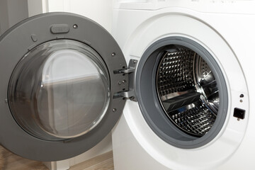 Modern white steel open washing machine close-up.