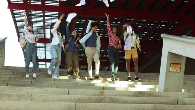 multiracial students who finish the course throw papers in the air to celebrate the end of the degree
