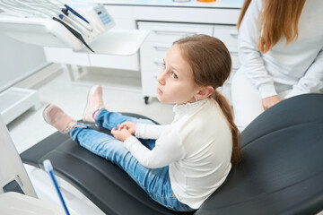Sad little girl sitting in dentist office