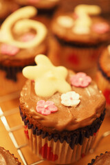 Freshly baked cupcakes on baking rack with icing and decoration