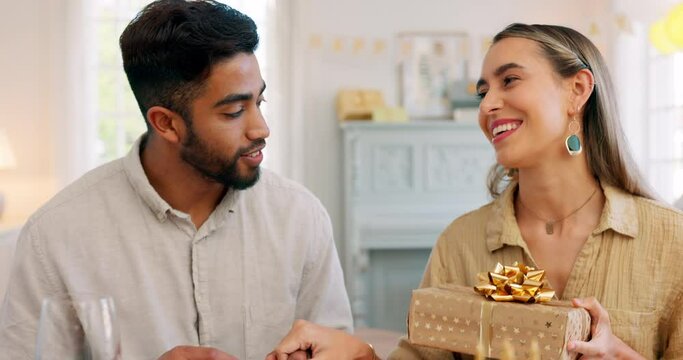 Gift, dinner and couple talking about birthday, anniversary or celebration at a dining room table in house. Happy, smile and young man and woman speaking about present, gratitude and love with food
