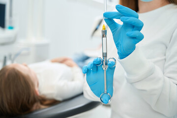 Dentist preparing to administer local anesthetic to patient - obrazy, fototapety, plakaty