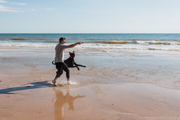 Man with dog running near sea