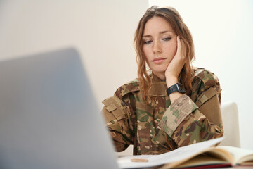 Woman in a camouflage uniform works with working documents and a gadget