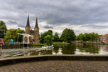 Panoramic view of a boat navigating canal against Oostport (East Gate) Delft, Netherland