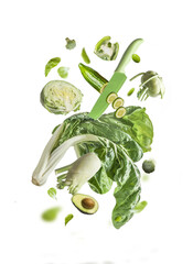 Isolated of flying green vegetables ingredients with knife. Balancing veggies fennel, lettuce,...