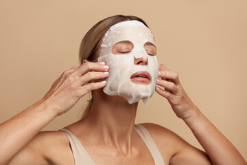 Beauty Woman Applying Face Mask. Portrait Of Beautiful Girl Applying White Sheet Mask at Healthy...