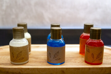 Small bottles of shampoo and shower gel in different colors in the foreground