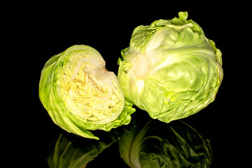 Obraz premium One whole and one half head of fresh cabbage, macro, isolated on black background.