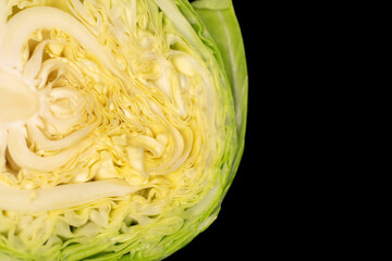 One half head of fresh cabbage, macro, isolated on black background.