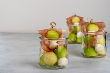 Jarcuterie is this appetizer recipe idea. Parma ham with melon on the skewer, mozzarella and basil for one portion, collected in a jar, ideal for parties, appetizers.