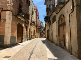 Fototapeta na wymiar Montblanc, Spain, June 2019 - A large brick building with a clock on the side of the street