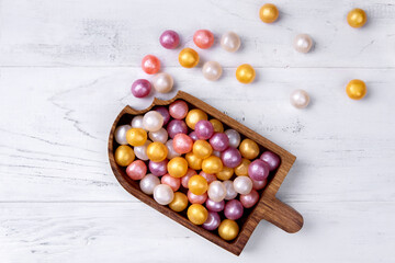 Mixed colorful round candy on white wooden background in wooden plate in the form of ice-cream. Flat lay, top view. Place for the text.