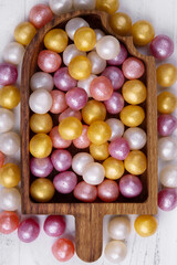 Mixed colorful round candy on white wooden background in wooden plate in the form of ice-cream. Flat lay, top view. Place for the text.