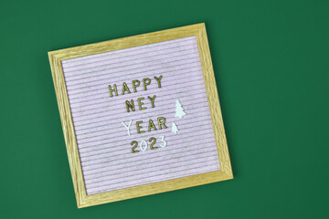 Wish text in English Happy New Year 2023 on felt letter board on green background. Top view. Copy space for text. Selective focus.