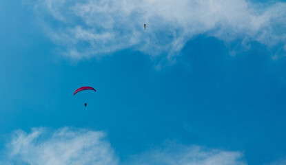 Naklejka na ściany i meble paragliding pilot flying high in the blue sky with clouds