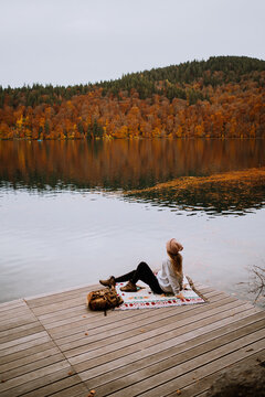 A girl on a pond by the lake in fall with orange tree forest 