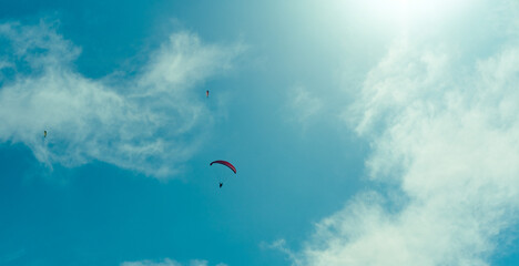 paragliding pilot flying high in the blue sky with clouds