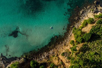 Obraz premium Aerial view of a rocky beach with calm and turquoise sea water with two paddle surfs floating