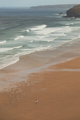 surfer walking on empty beach waves and sand