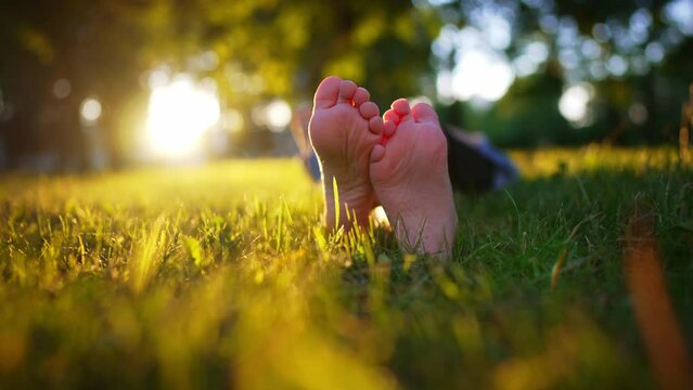 Bare feet of a child in the green grass of a sunny park in summer. The concept of the first steps, happy childhood. Summer vacation.