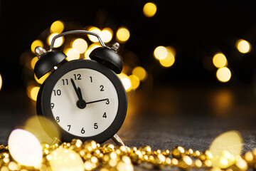 christmas composition with clocks and lights of garlands on a dark background with copy space.