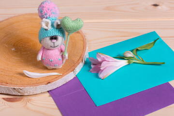 Knitted bunny in a hat on a blue background. bouquet of daisies in the background