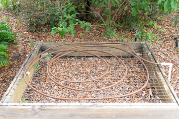 A wooden flower box with small copper coiled in circles fixed to a water system. The micro irrigation system allows water to drip slowly into the roots of the flowers or vegetables through the soil.  - obrazy, fototapety, plakaty