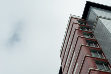 The exterior wall of a contemporary commercial style building with aluminum metal composite panels and glass windows. The futuristic building has engineered diagonal cladding steel frame panels.