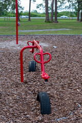 Colorful red metal durable children's playground equipment, teeter totter, or seesaw in a park. The...