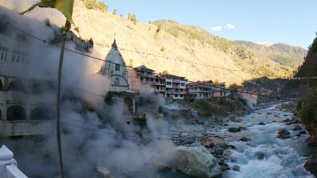 4K wide angle shot of Shiva temple besides the Paravati river at Manikaran in Himachal Pradesh, India. Steam from hot springs near the temple in front of temple. Shiva temple at Manikaran in winter. 