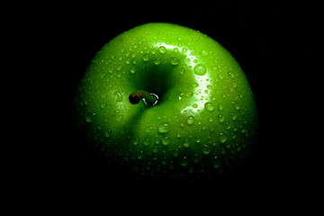 Green apple with water drops in the dark. Wet green apple on a dark background