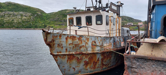 An old rusty ship is tied to the shore with ropes.